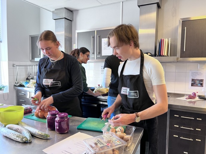 Jongen en meisje zijn groenten aan het snijden in de keuken.