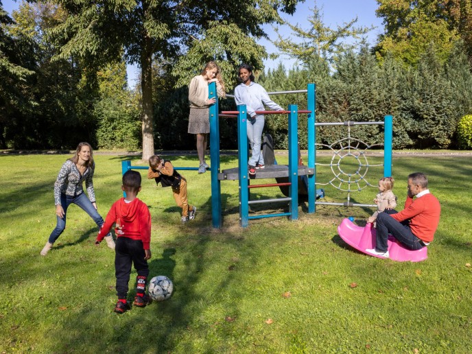 Ouders spelen met hun kinderen in de speeltuin.