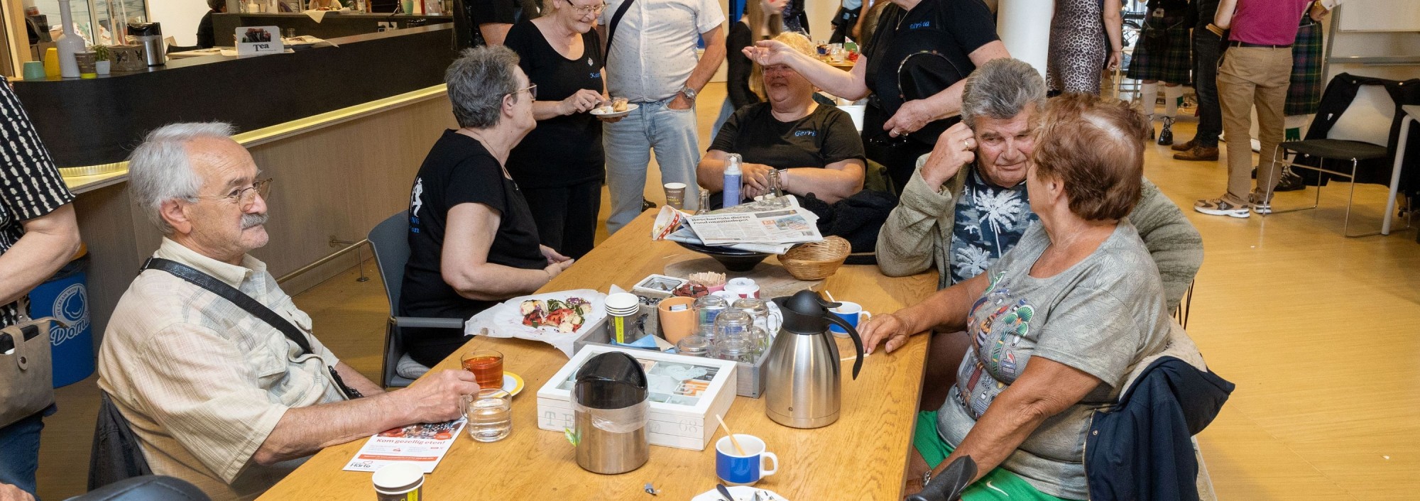 Groep mensen drinkt samen aan tafel koffie.