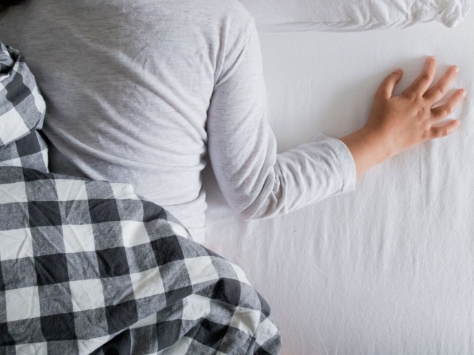 Matras met stukje dekbed en rug en arm van een kind,