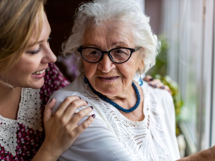 Jonge vrouw legt handen op schouders van oudere vrouw.