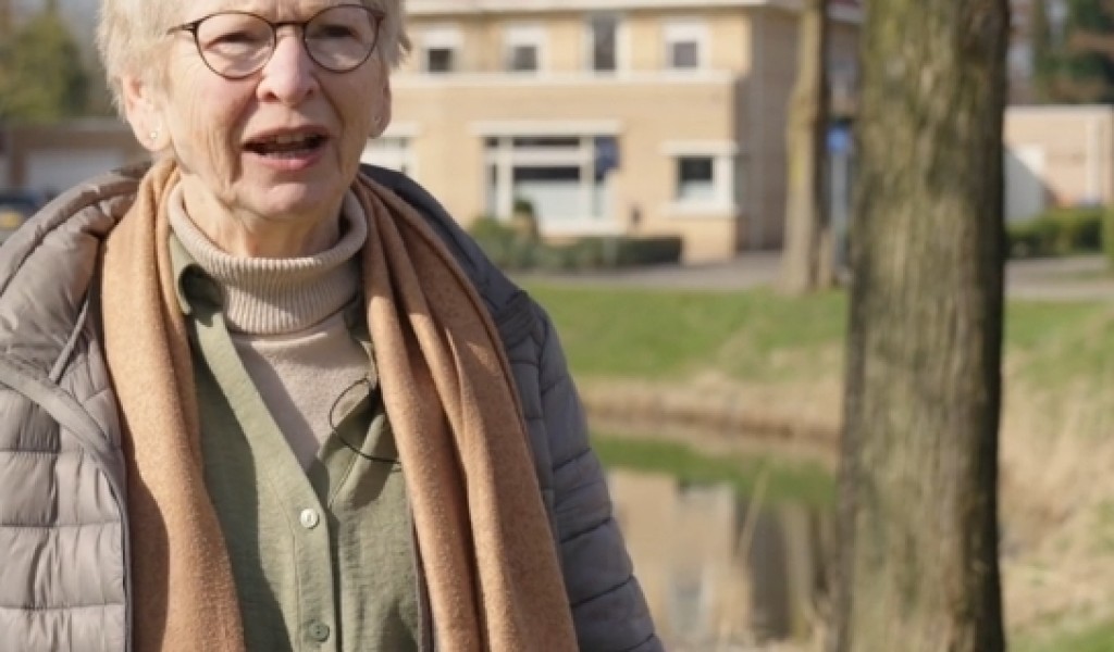 Mevrouw met op de achtergrond een huis, vijver en en boom