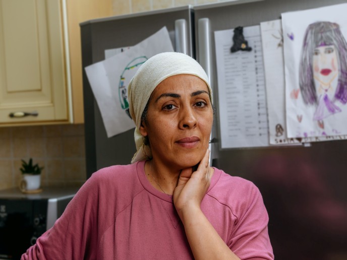 Vrouw met hoofddoek houdt hand onder haar kin.