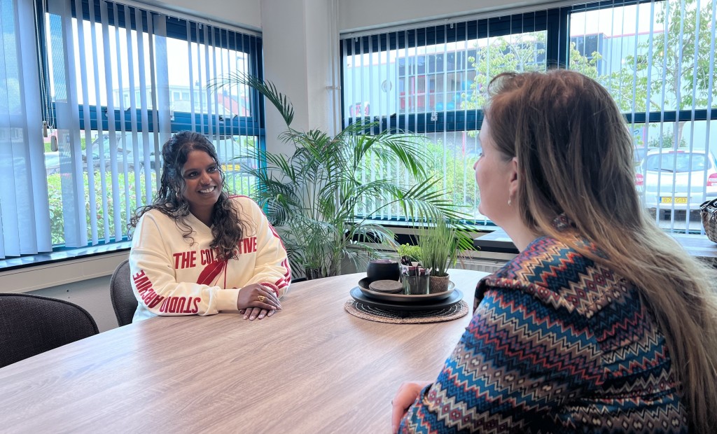 Twee vrouwen zijn aan tafel in gesprek.