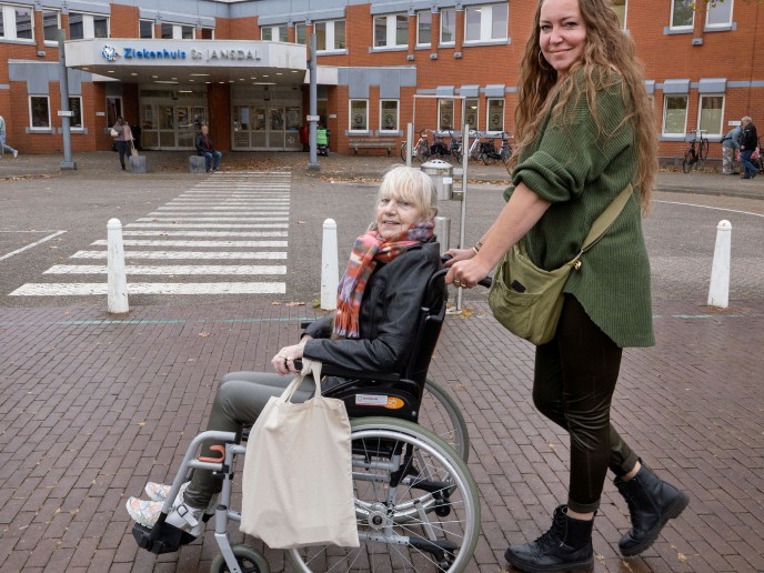 Vrouw duwt vrouw in rolstoel naar ziekenhuis