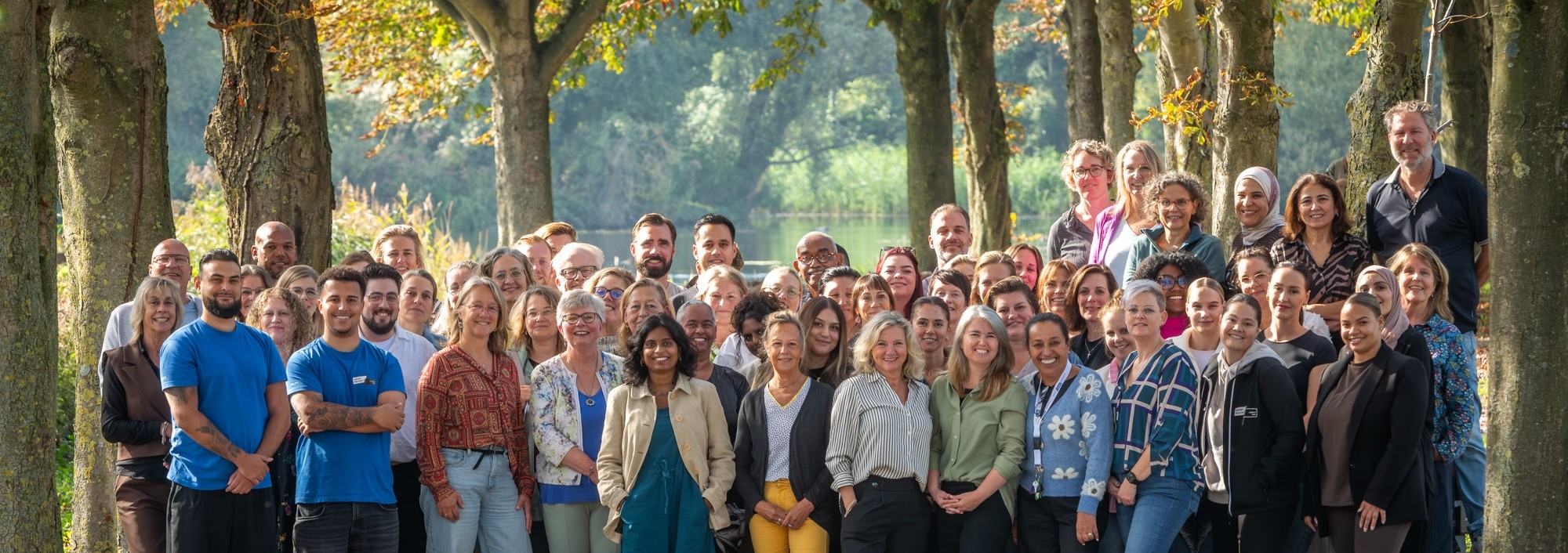 Mensen met roze hesjes houden vlag met logo van Welzijn Lelystad vast.