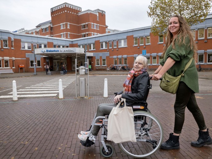 Vrouw duwt andere vrouw in rolstoel