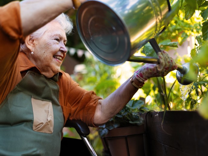 Oudere vrouw geeft planten water.