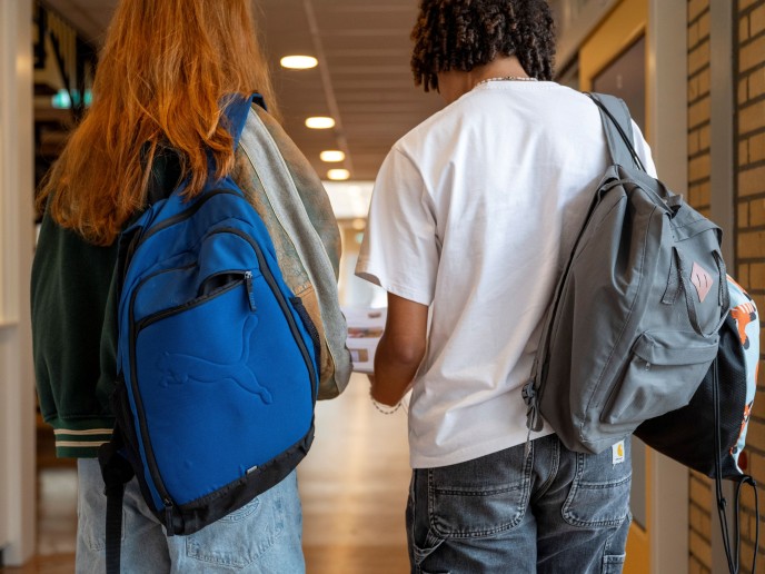 Jongen en meisje met rugtas in school.