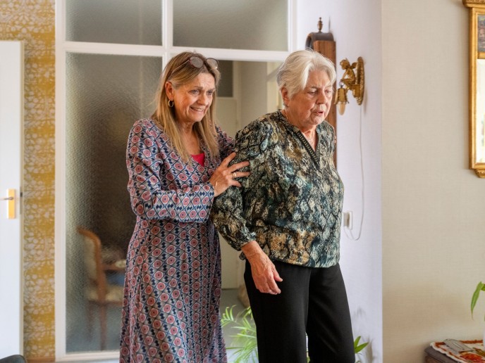 Vrouw helpt oudere vrouw terwijl ze loopt.
