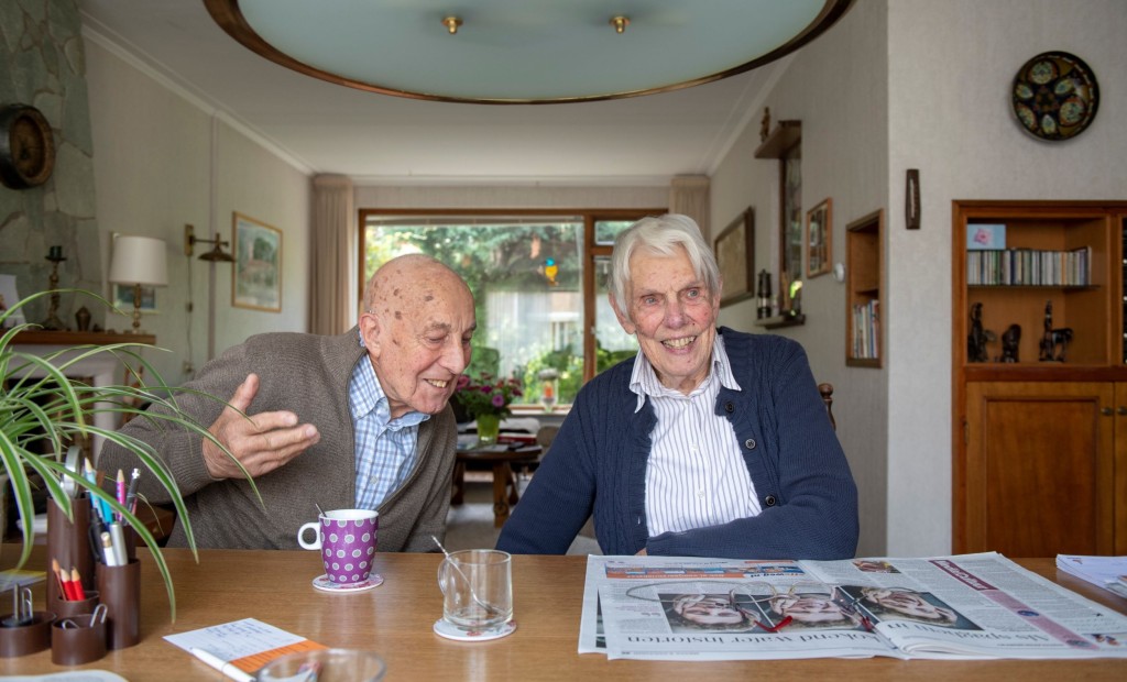 Twee mannen zitten samen aan tafel en lezen de krant.