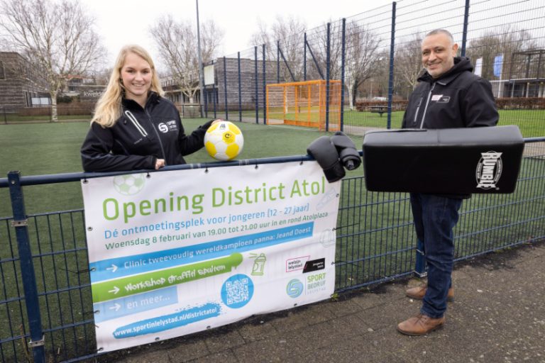 Een medewerker van Sportbedrijf Lelystad en een jongerenwerker van Welzijn Lelystad staan op een Cruijf Court naast een spandoek waarop staat: Opening District Atrol