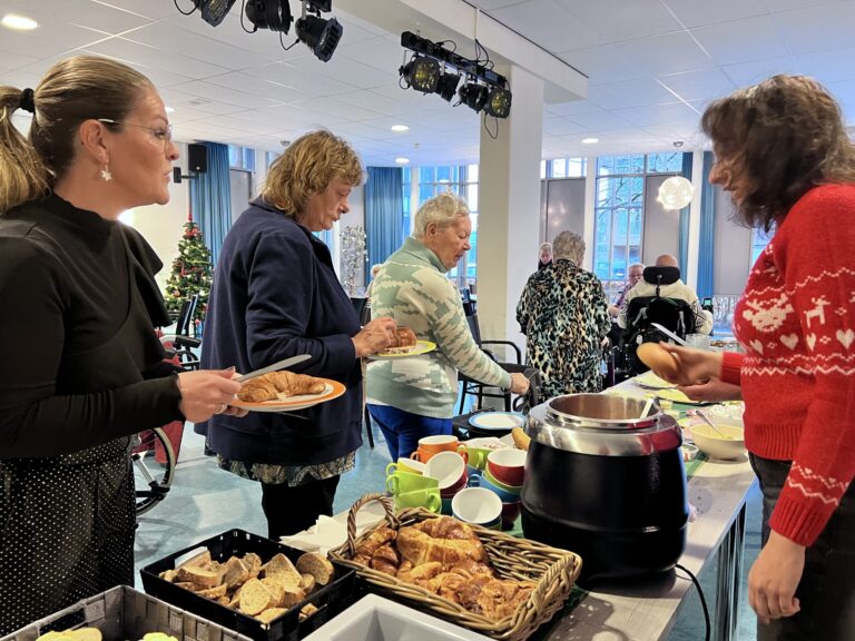 Mensen kiezen eten van een tafel vol eten.